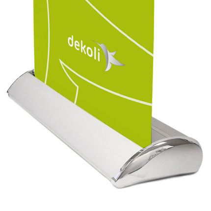 Detaillierte Ansicht des eleganten, gebogenen Fußes eines Roll-Up Banners von dekolli mit glänzendem, silbernem Finish, der ein lebhaft grünes Banner mit dem Firmenlogo trägt.
