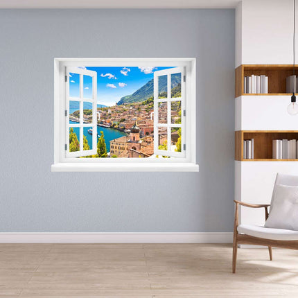 Öffnen Sie das Fenster zu Ihrer Fantasie! Selbstklebendes gedrucktes Wandtattoo mit atemberaubender Aussicht auf das malerische Dorf Porto di Limone und den sonnenverwöhnten Gardasee, dekorativ platziert in einer Leseecke neben einem Bücherregal. Die ideale Dekoration für Momente der Entspannung.