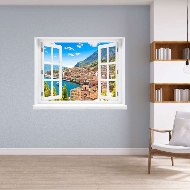 Öffnen Sie das Fenster zu Ihrer Fantasie! Selbstklebendes gedrucktes Wandtattoo mit atemberaubender Aussicht auf das malerische Dorf Porto di Limone und den sonnenverwöhnten Gardasee, dekorativ platziert in einer Leseecke neben einem Bücherregal. Die ideale Dekoration für Momente der Entspannung.