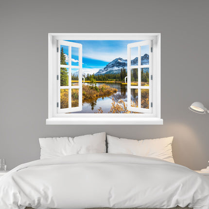 In Form geschnittener Wandaufkleber mit einem offenen Fenster, mit Blick auf einen Fluss in den italienischen Bergen an einem schönen Herbsttag, an einer grauen Wand hinter einem Bett. Eine interessante Dekoration für erholsame Stunden.
