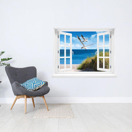 Lassen Sie sich von der Magie des Meeres verzaubern! Selbstklebendes Fenstermotiv mit Blick auf einen Strand im Sommer, dem endlos weitem Meer und zwei Möwen, die über den Strand fliegen, als Dekoration in einer Leseecke neben einem Sessel. Die ideale Dekoration für Ruhe, Urlaubsstimmung und Entspannung. 